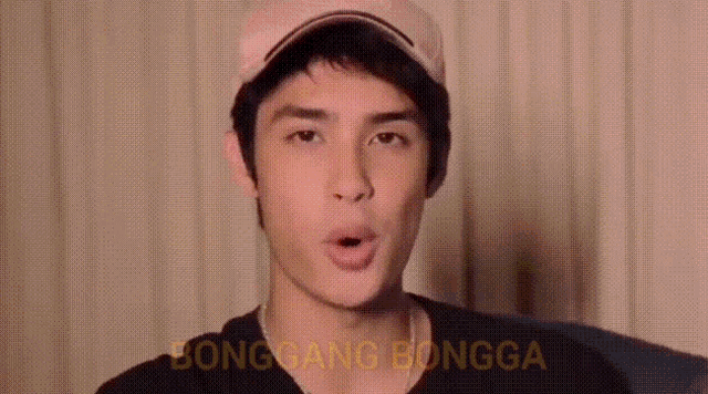 a young man wearing a baseball cap is making a funny face and the words bonggang bongga are visible behind him .