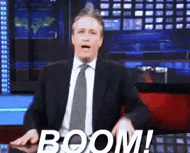 a man in a suit and tie is making a funny face with the word boom behind him