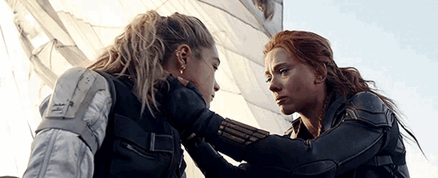 two women are touching each other 's faces while standing next to each other .