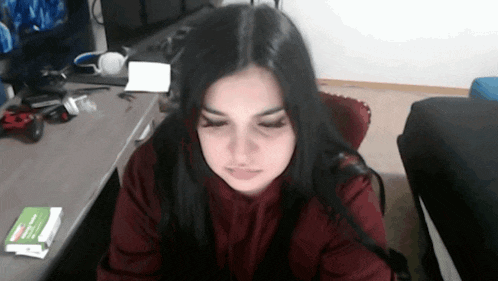 a girl with long black hair is sitting at a desk with a book on it