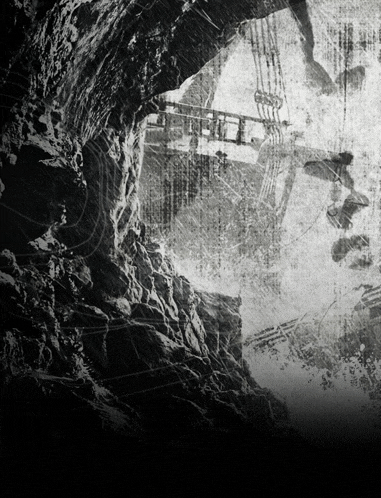 a black and white photo of a cave with a few people