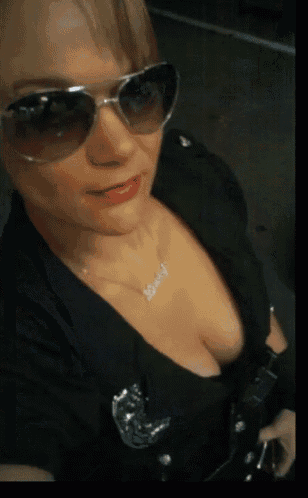 a woman is wearing sunglasses and a necklace that says lovely
