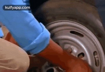 a person is changing a tire on a car with their hands .