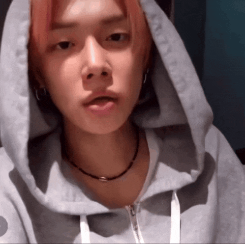 a young man with pink hair wearing a grey hoodie