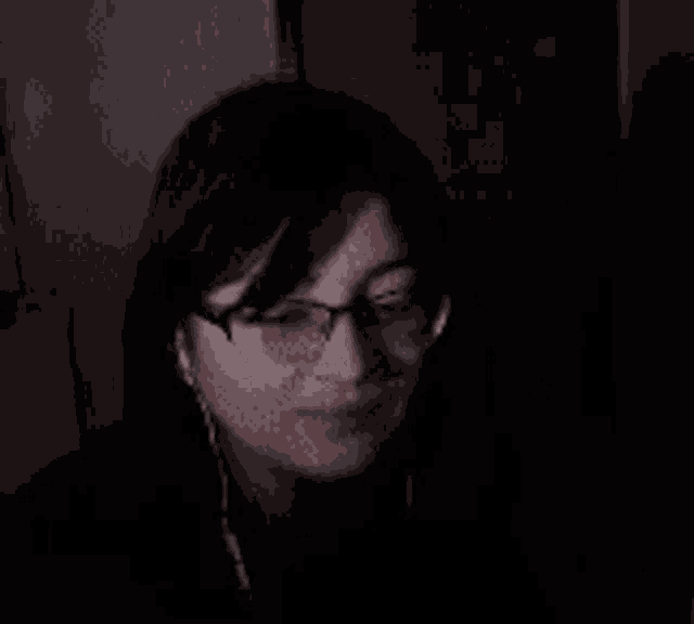 a woman wearing glasses and earbuds is covering her nose with her hand
