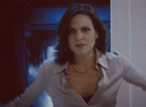 a woman wearing a pearl necklace is standing in a dark room