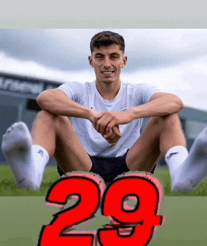 a man sits with his legs crossed and the number 29 is behind him