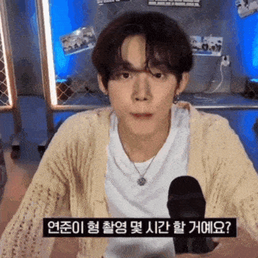 a young man is sitting in front of a microphone with korean writing on it .