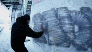 a man in a black jacket is spraying graffiti on a wall with the letter a