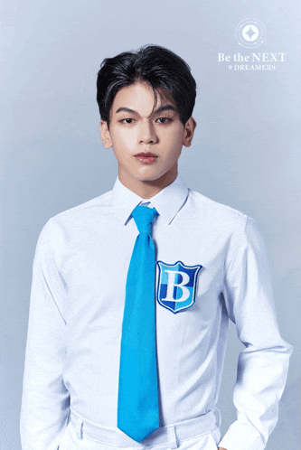 a young man wearing a white shirt and blue tie with the letter b on his shirt