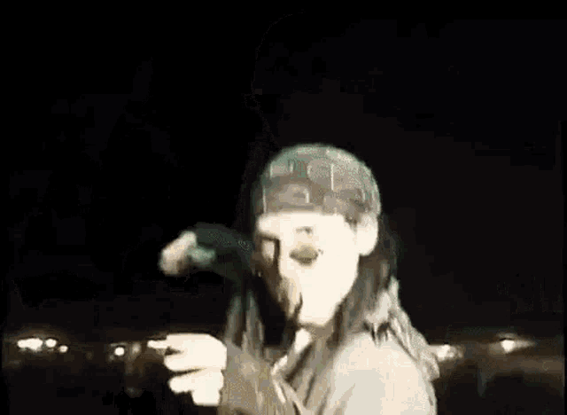 a man wearing a bandana is smoking a cigarette on a stage at night .