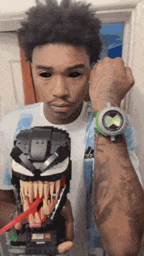 a man is wearing a ben 10 watch and holding a lego venom mask