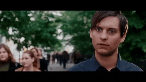 a man in a black shirt is standing in front of a crowd of people on a city street .