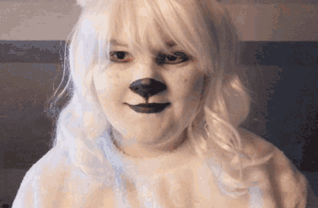 a woman wearing a white wig with a dog face painted on her face