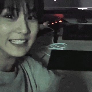 a woman is smiling while sitting in front of a computer screen