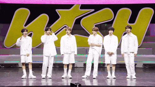 a group of young men stand on a stage in front of a sign that says " way "