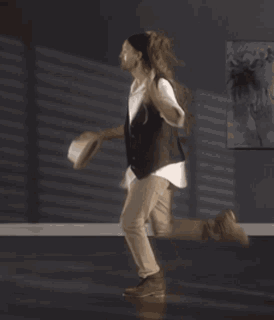 a man in a white shirt and tan pants is running with a hat
