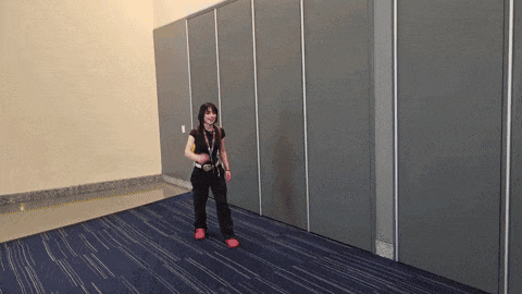 a woman is standing in a room with a blue carpet and a gray wall