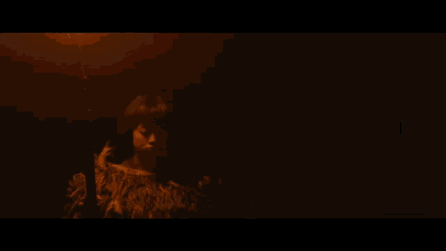 a young boy in a feathered costume is holding a spear in a dark room .