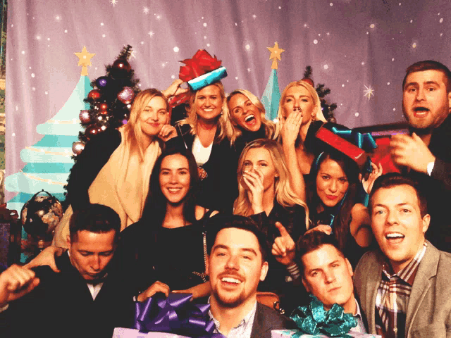 a group of people are posing for a picture in front of a christmas tree