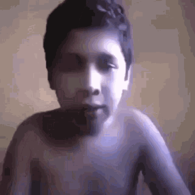 a boy without a shirt looks at the camera