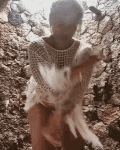 a woman in a white sweater is holding a white feather in her hands .