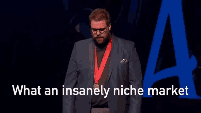 a man in a suit and medal around his neck stands in front of a blue letter a
