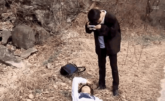 a man is taking a picture of a woman laying on the ground ..