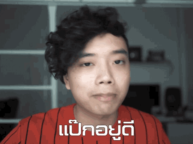 a man wearing a red and black striped shirt has a message in a foreign language on his shirt
