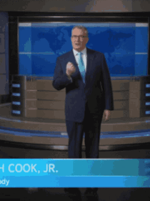 a man in a suit and tie is standing in front of a world map
