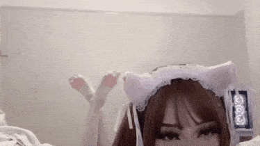 a girl is laying on a bed wearing a cat ear headband and paws .