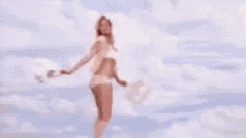 a woman in white underwear with a white tail on her butt is standing in front of a cloudy sky .