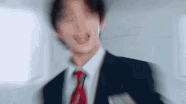 a blurry picture of a man in a suit and tie making a funny face .
