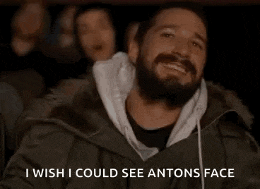 a man with a beard is sitting in a movie theater watching a movie and smiling .