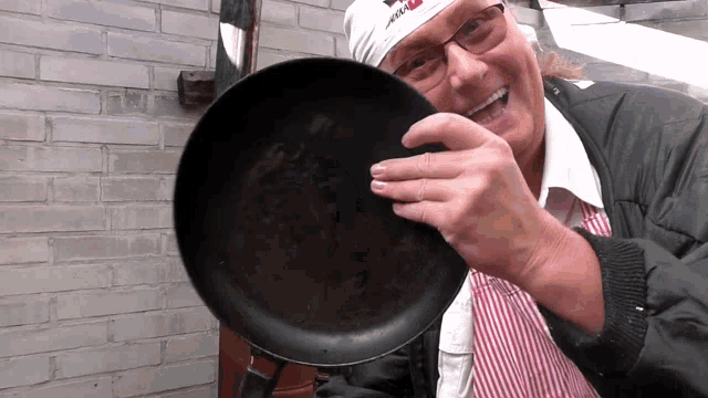 a man holding a frying pan with a bandana on his head that says ' apollo ' on it