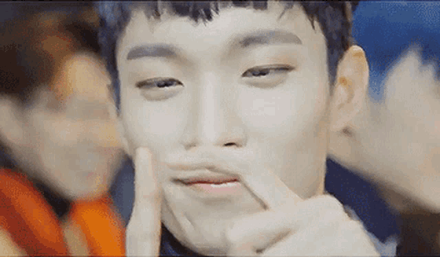 a young man is making a funny face with his fingers in his mouth .