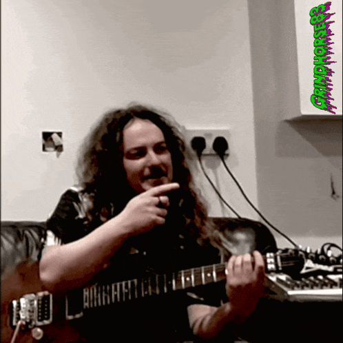 a man playing a guitar with a green sticker that says ' candyhouse ' on it
