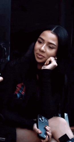 a woman sitting on the floor holding a phone