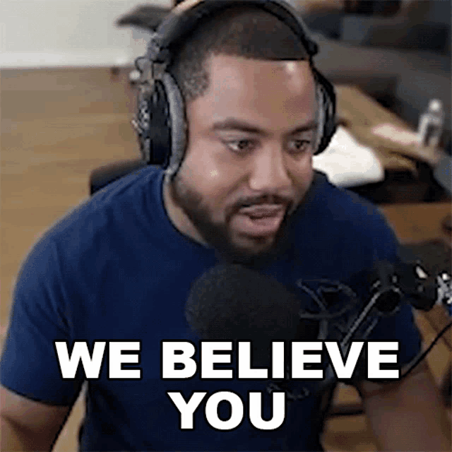 a man wearing headphones and a blue shirt is talking into a microphone and saying `` we believe you '' .