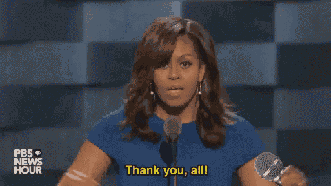a woman in a blue dress is giving a speech in front of a microphone and saying thank you all .
