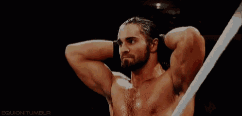 a man with a beard is holding his hands behind his head in a wrestling ring .