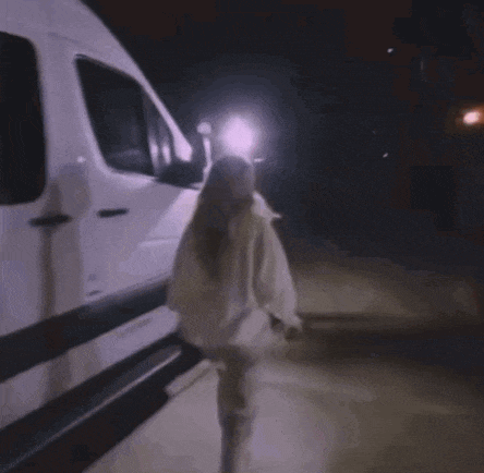 a woman is running towards a white van in the dark .