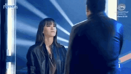a man and a woman are standing next to each other and looking at each other on a stage .