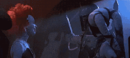 a group of people are standing next to each other in a dark room and talking to each other .