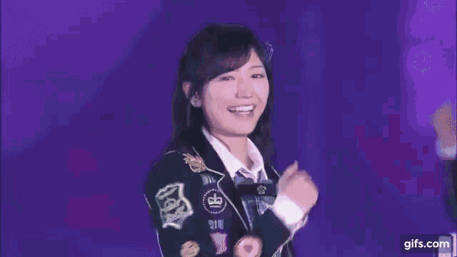 a close up of a woman 's face with a purple background pointing her finger .