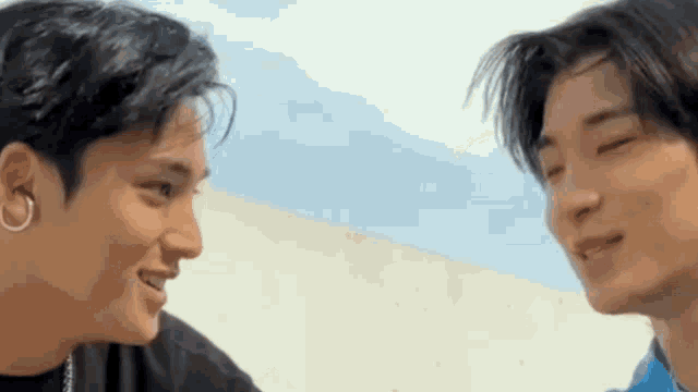 two young men are looking at each other and smiling while standing next to each other .