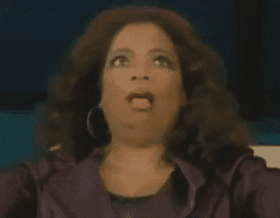 a woman with a surprised look on her face is wearing a purple jacket and hoop earrings .