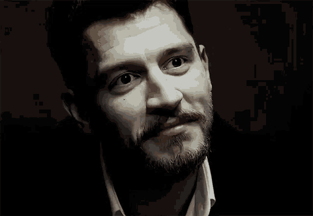 a man with a beard looks at the camera