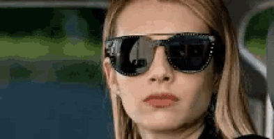 a close up of a woman wearing sunglasses and making a face .