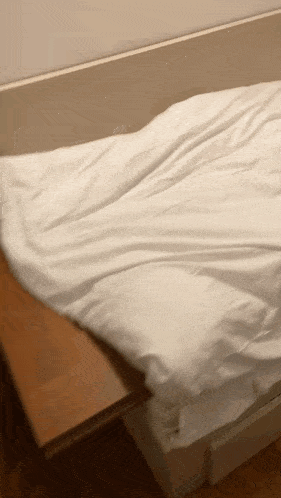 a person is making a bed with white sheets and pillows